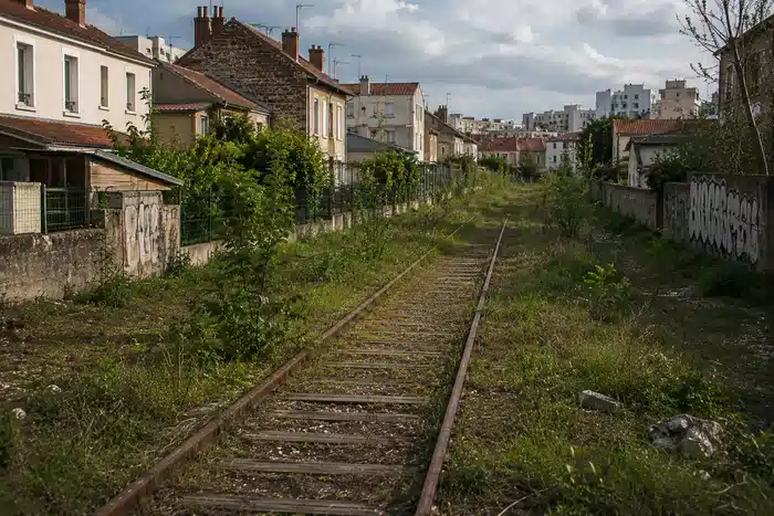 Ancienne voie ferrée en milieu urbain près de jardins et maisons