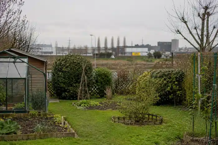 Jardin périurbain calme avec zone industrielle discrète au loin