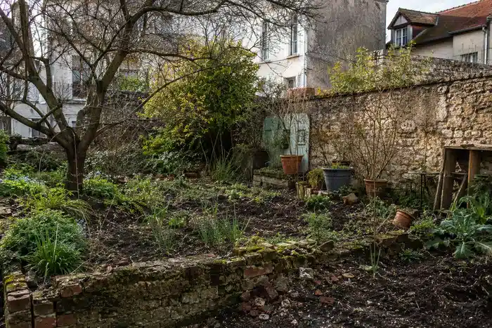 Ancien jardin urbain avec muret et remblais discrets